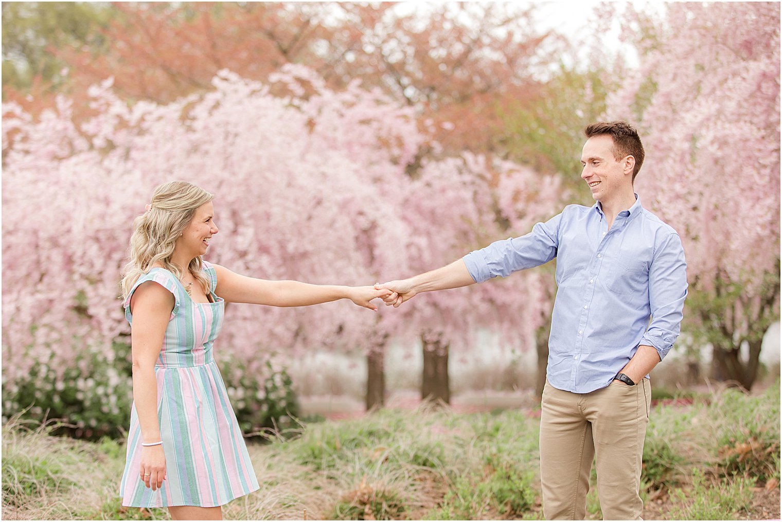 bride and groom hold hands by pink trees at Branch Brook Park