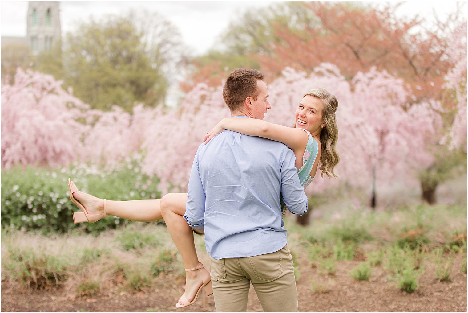 groom lifts bride up during engagement portraits at Branch Brook Park