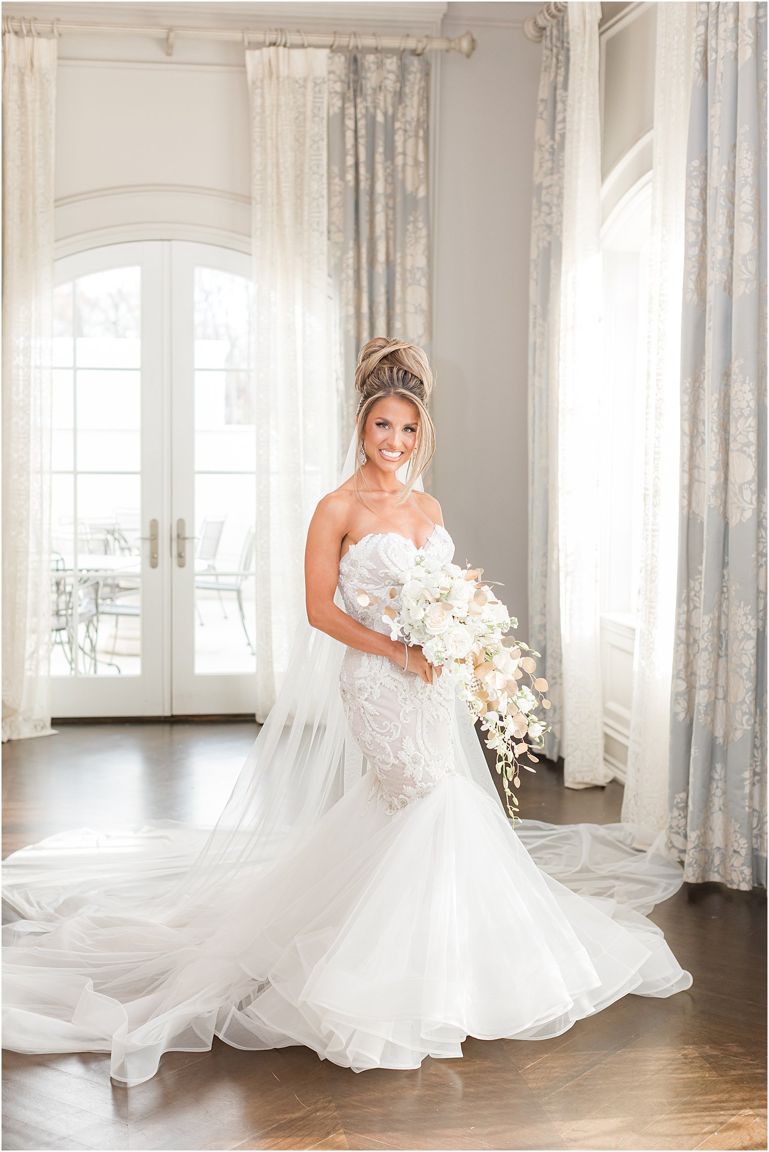bride holds cascading bouquet of white and gold flowers in bridal suite at Park Chateau Estate 