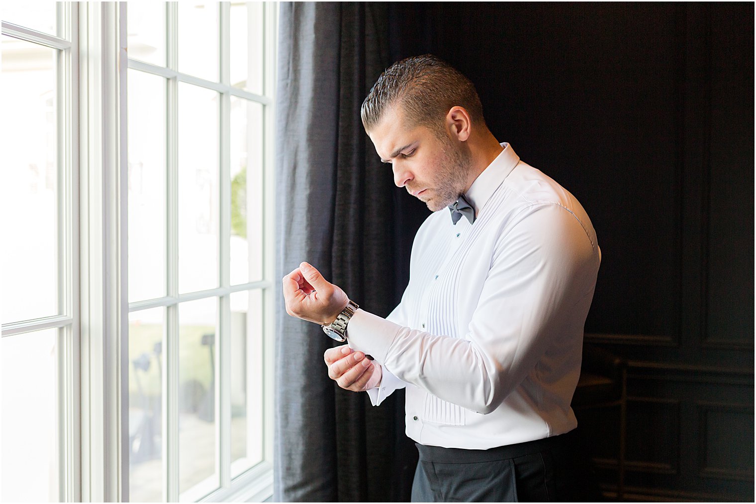 groom adjusts cufflinks before winter Park Chateau Estate wedding