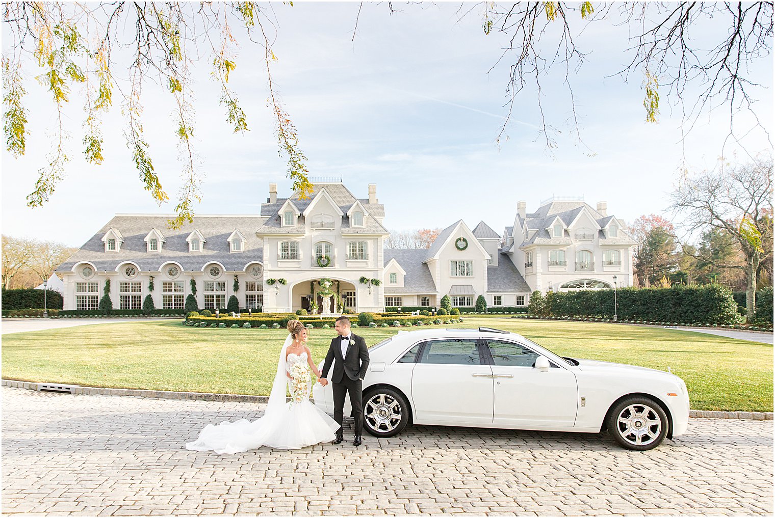 bride and groom hold hands by white car outside Park Chateau Estate 