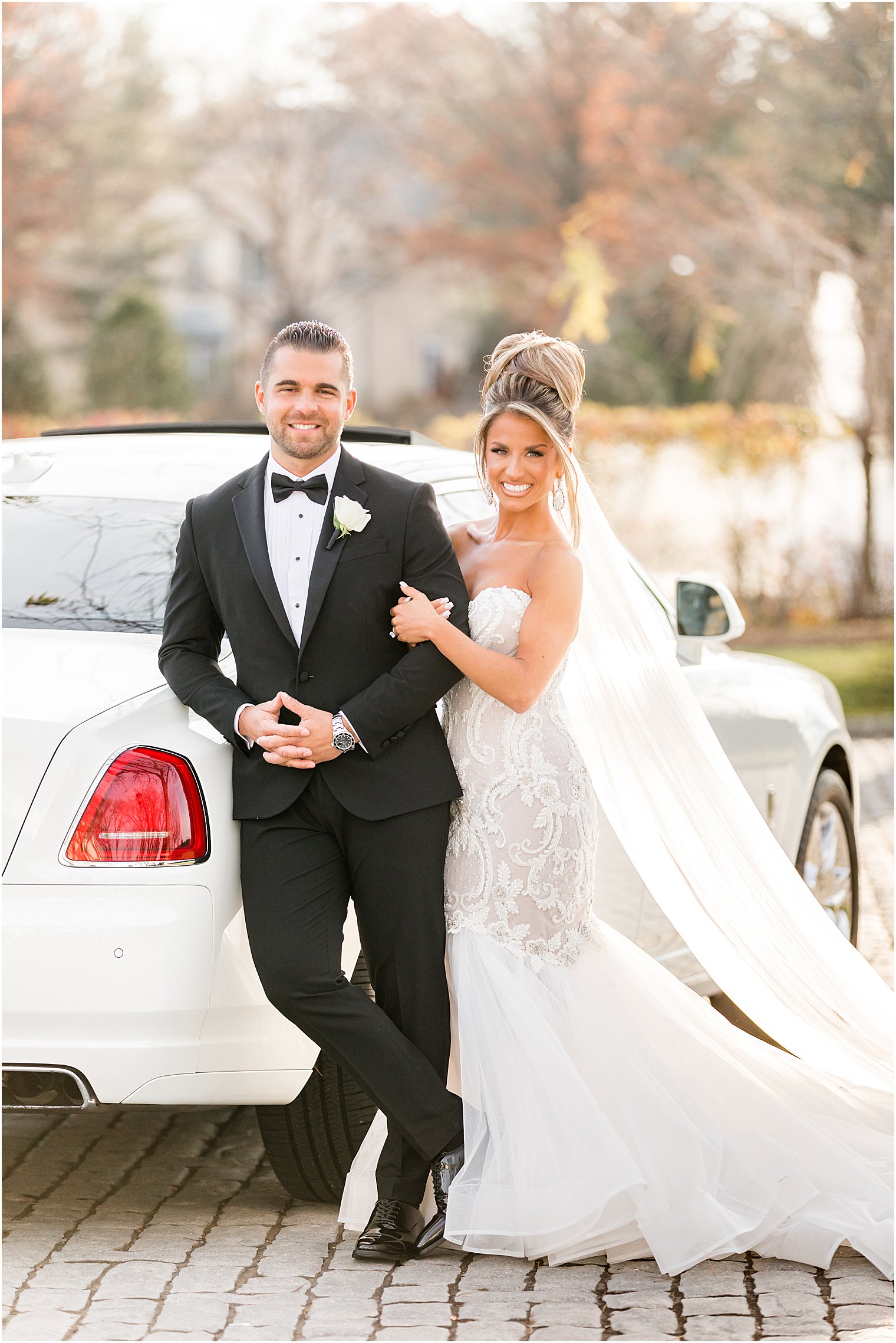 newlyweds lean against white car during portraits in December 