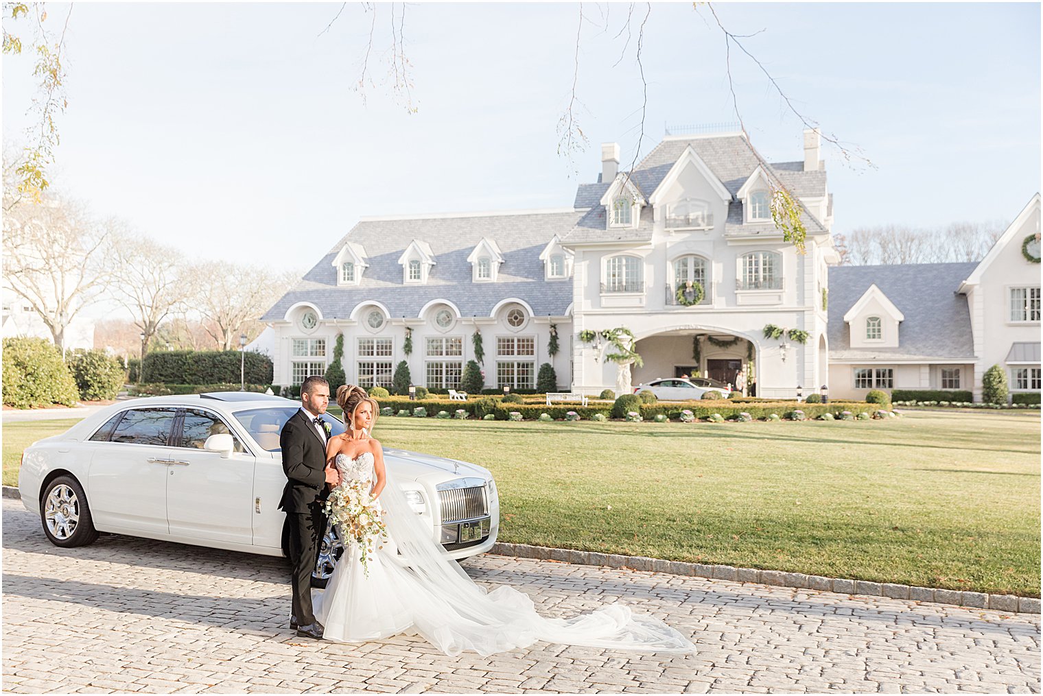 bride and groom stand by white car outside Park Chateau Estate 