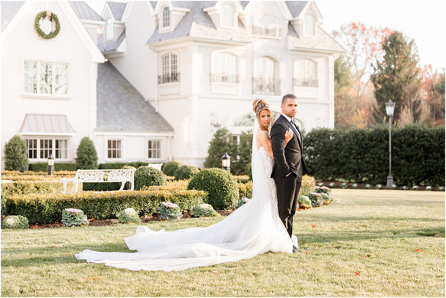 bride hugs groom from behind during wedding portraits on lawn of Park Chateau Estate 