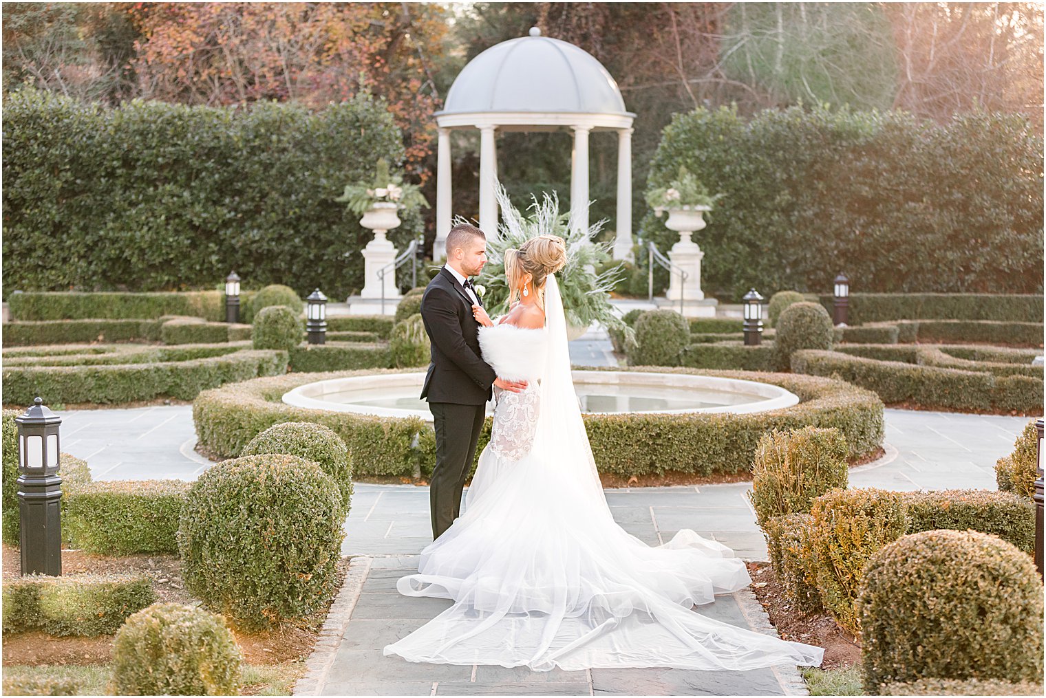 groom hugs bride in fur in the Park Chateau Estate gardens 