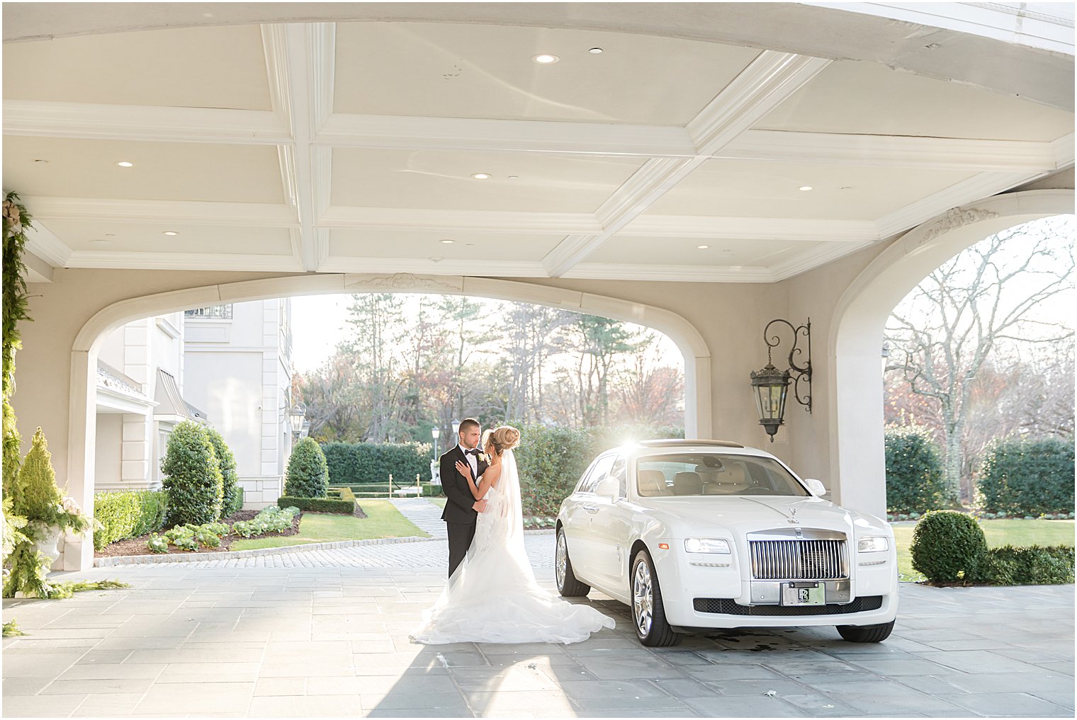 bride and groom hug near white car under awning at Park Chateau Estate 