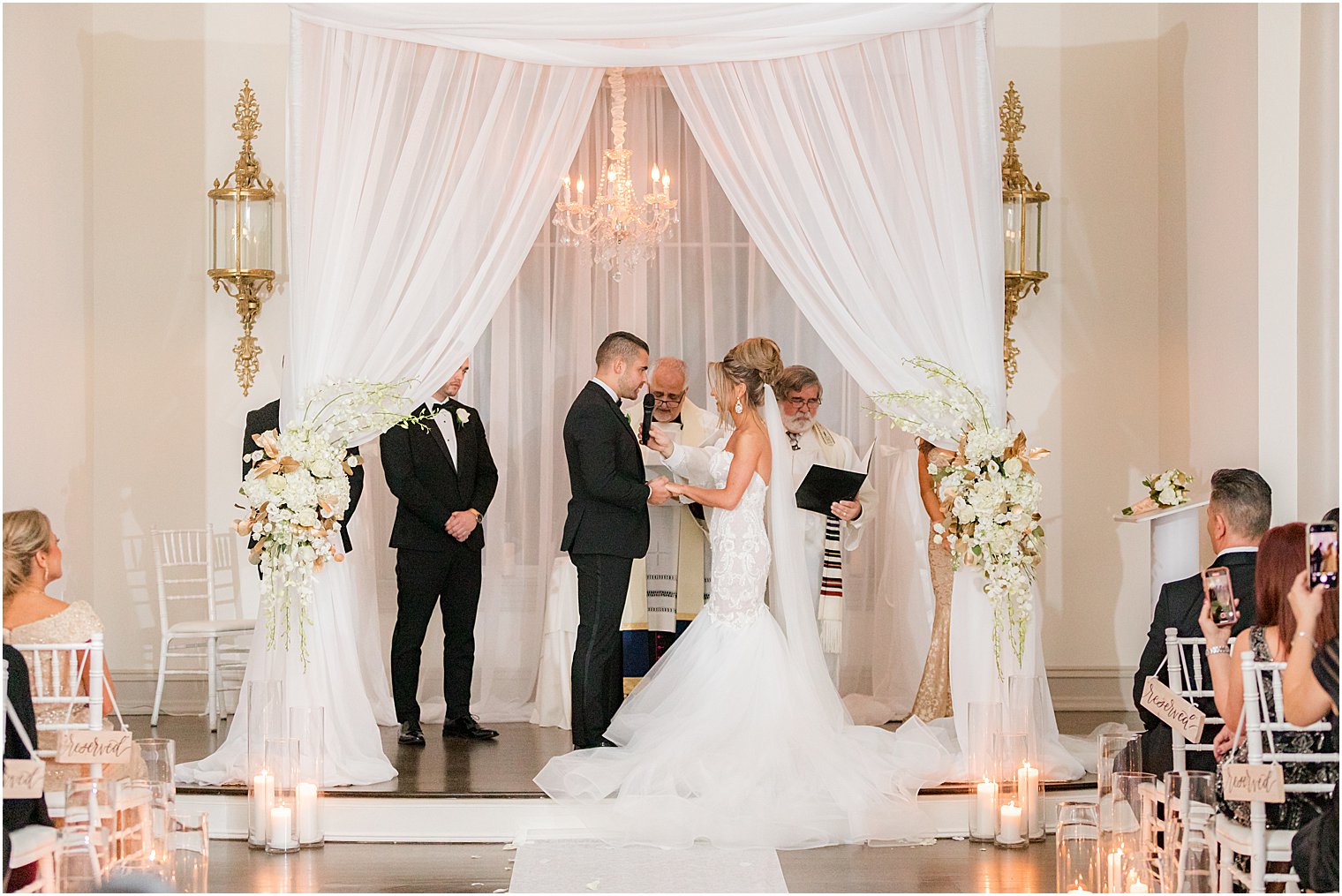 bride and groom exchange vows under canopy during winter wedding ceremony at twilight in Park Chateau Estate chapel