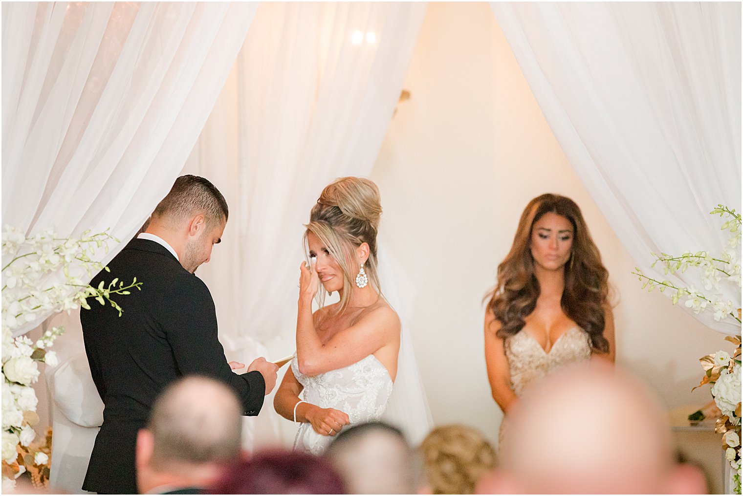 bride cries during winter wedding ceremony at twilight in Park Chateau Estate chapel