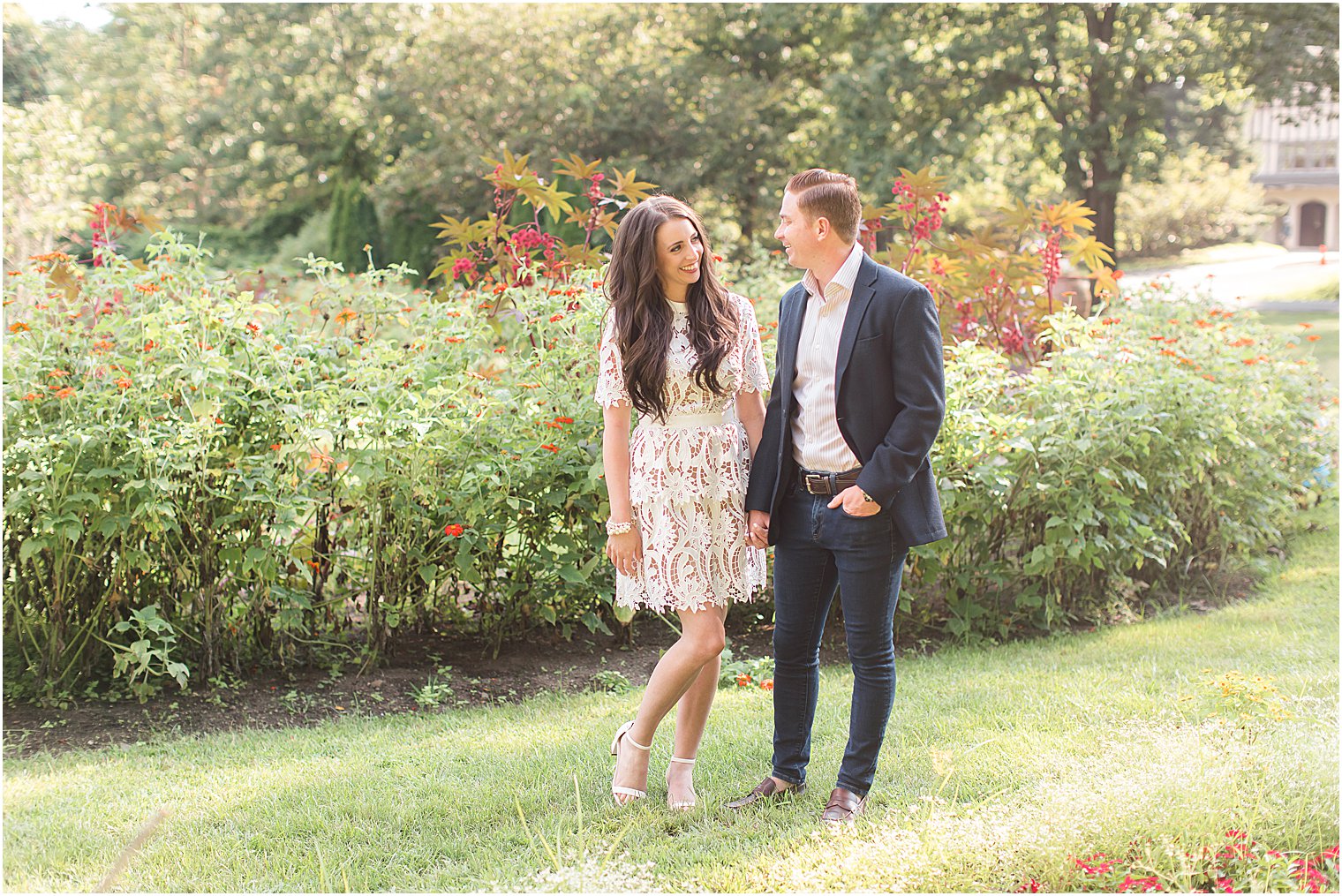 engaged couple holds hands walking through Skylands Manor gardens