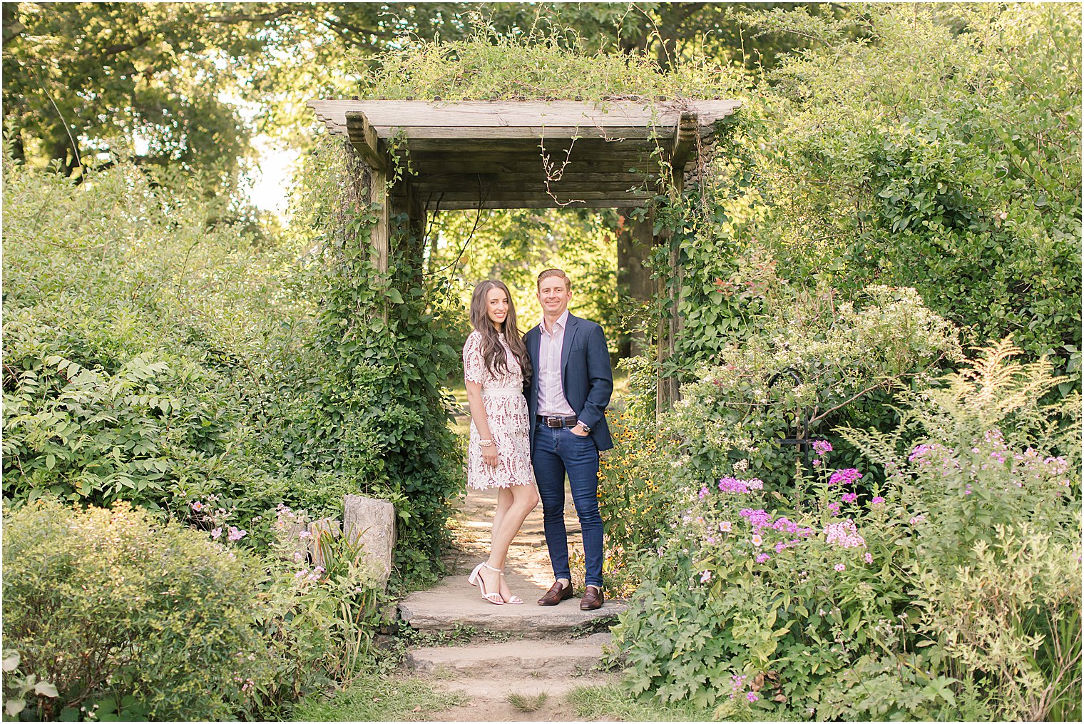 bride and groom stand near wooden arbor at Skylands Manor