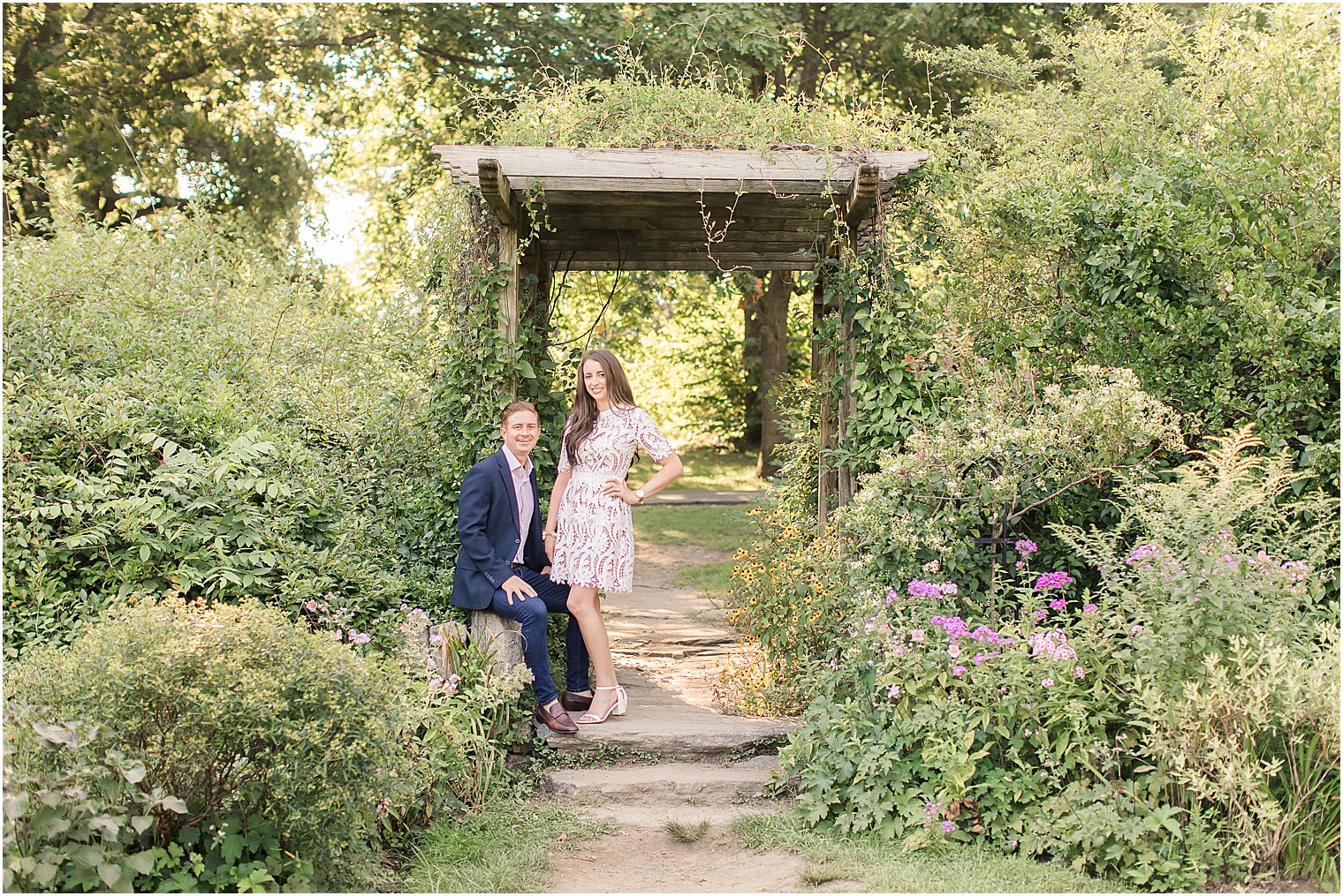 couple poses by wooden arbor in gardens of Skylands Manor