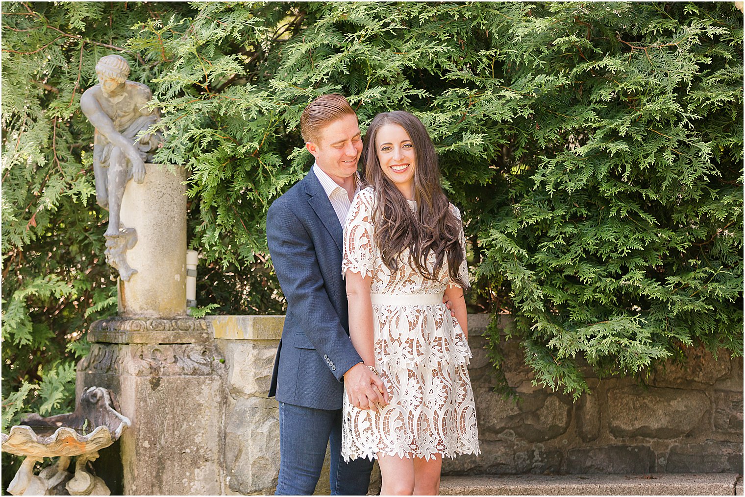 bride and groom hold hands by stone seat at Skylands Manor