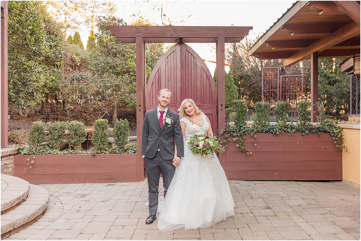 bride and groom walk by red gate at Stone House at Stirling Ridge