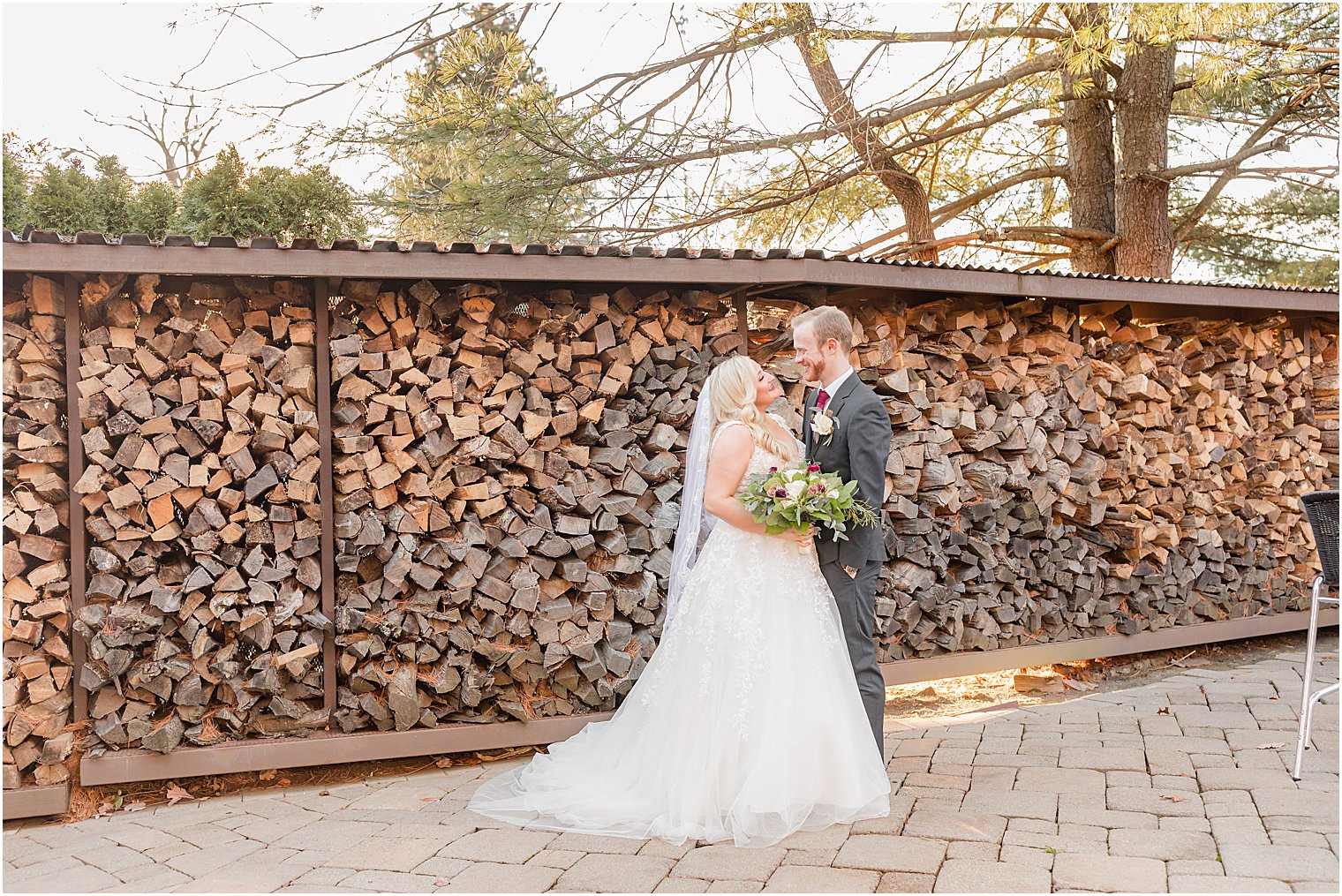 bride and groom pose by fire wood at Stone House at Stirling Ridge