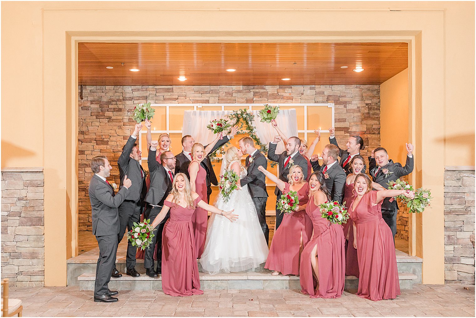 newlyweds kiss while bridal party cheers at Stone House at Stirling Ridge