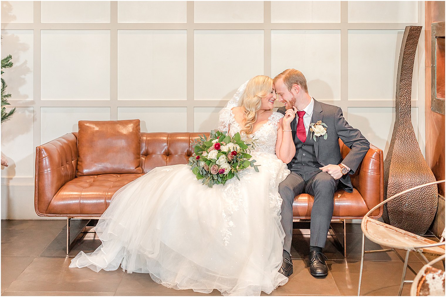 bride and groom sit on leather couch
