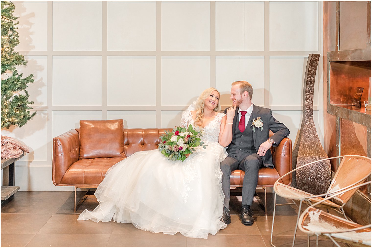 bride and groom sit together on leather couch at the Stone House at Stirling Ridge