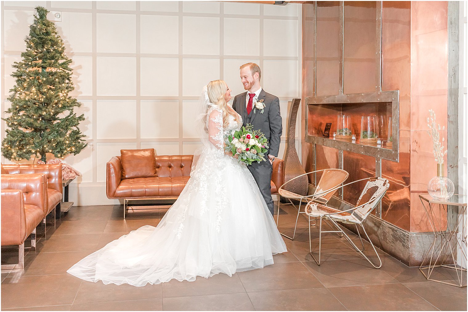 newlyweds smile at each other by fireplace at the Stone House at Stirling Ridge