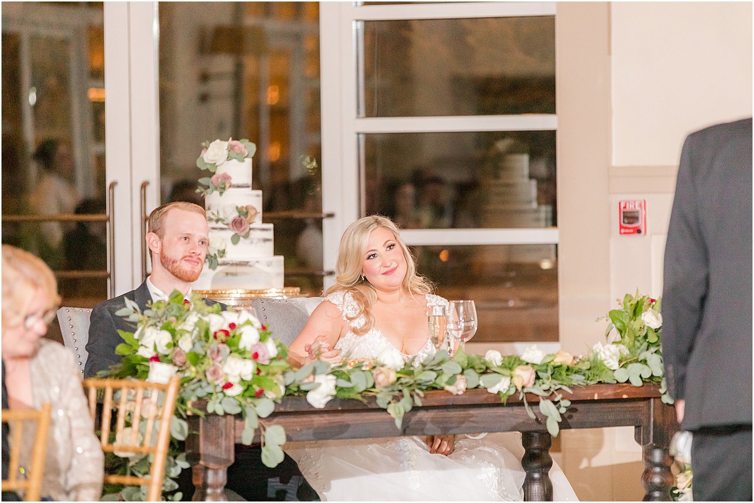 newlyweds listen to wedding reception toasts