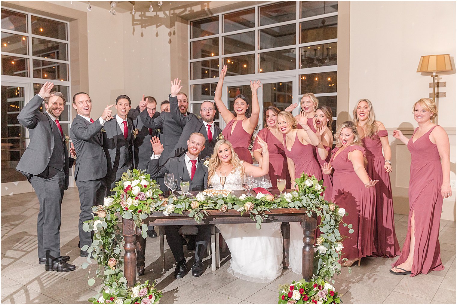newlyweds sit at table with wedding party surrounding them