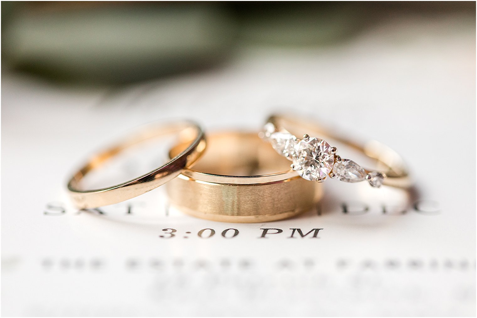 gold wedding bands rest on invitation suite in East Brunswick NJ