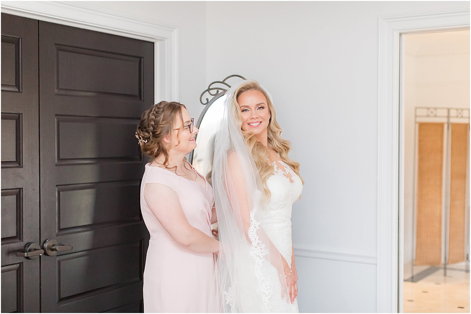 sister helps bride with wedding gown