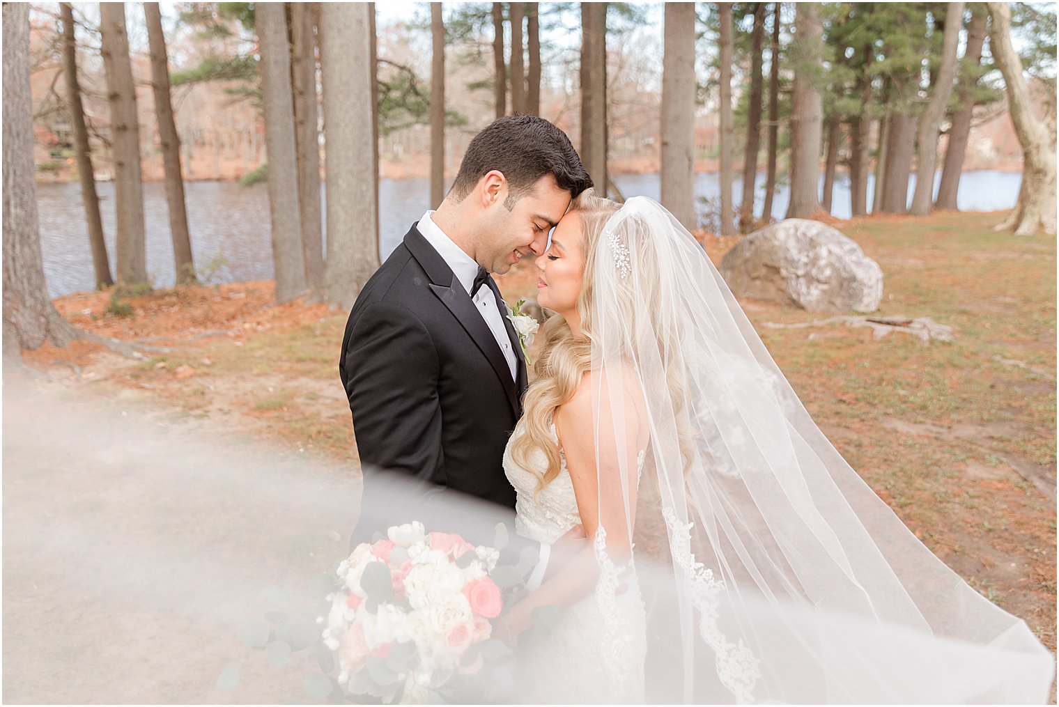 bride and groom touch foreheads together during portraits with bride's veil draped around them