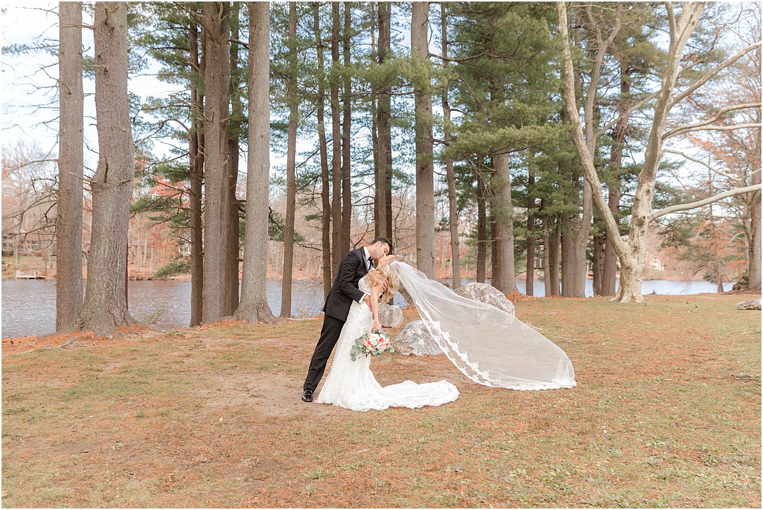 bride and groom kiss with bride's veil floating behind her