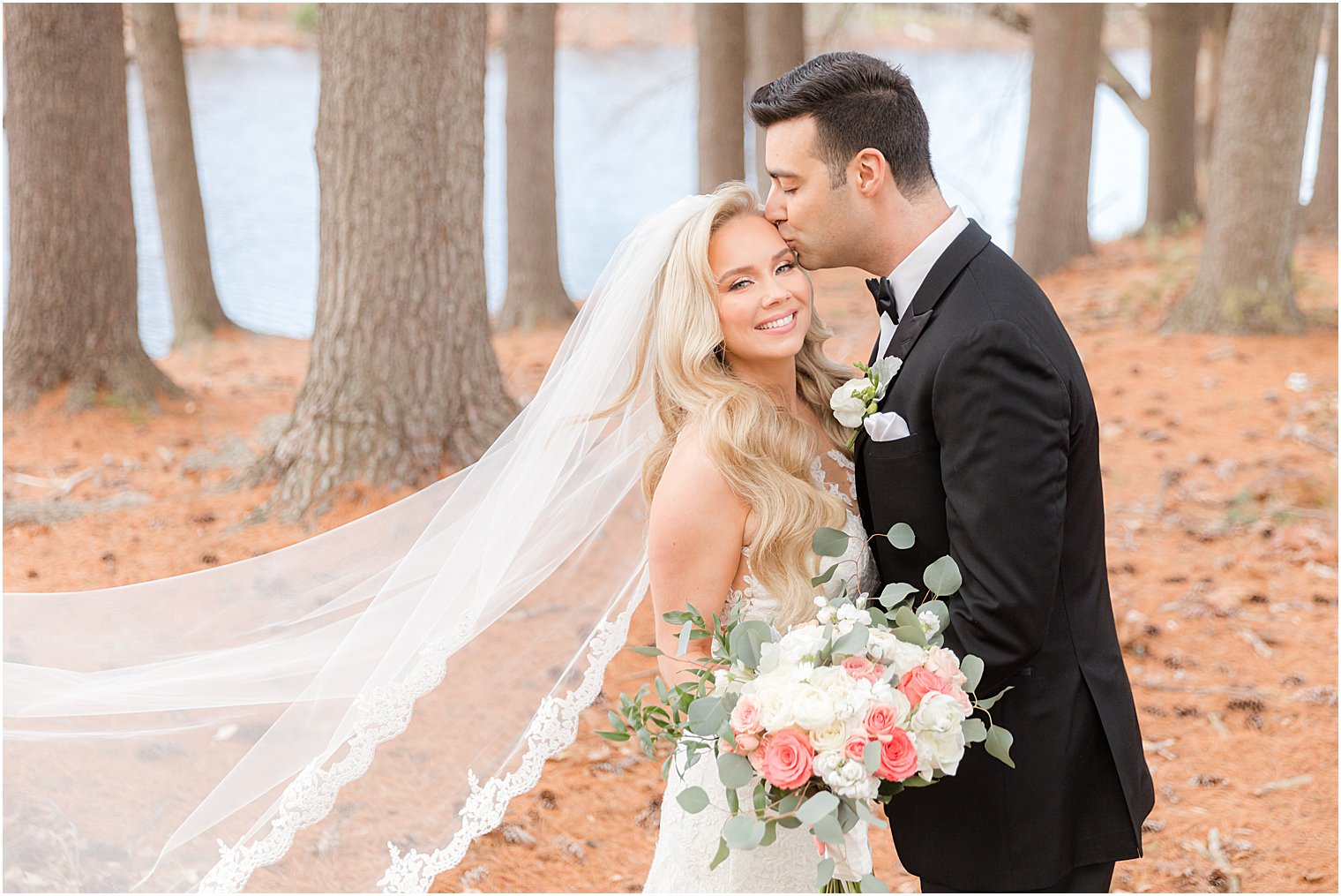 groom kisses bride's temple during NJ wedding portraits at the Estate at Farmington Lake