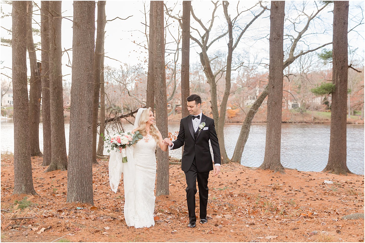 couple holds hands walking through the woods at the Estate at Farmington Lake