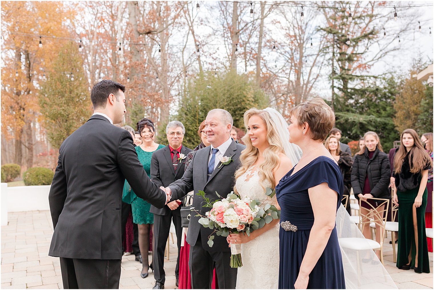 father of bride shakes groom's hand giving away bride during outdoor wedding ceremony in East Brunswick NJ