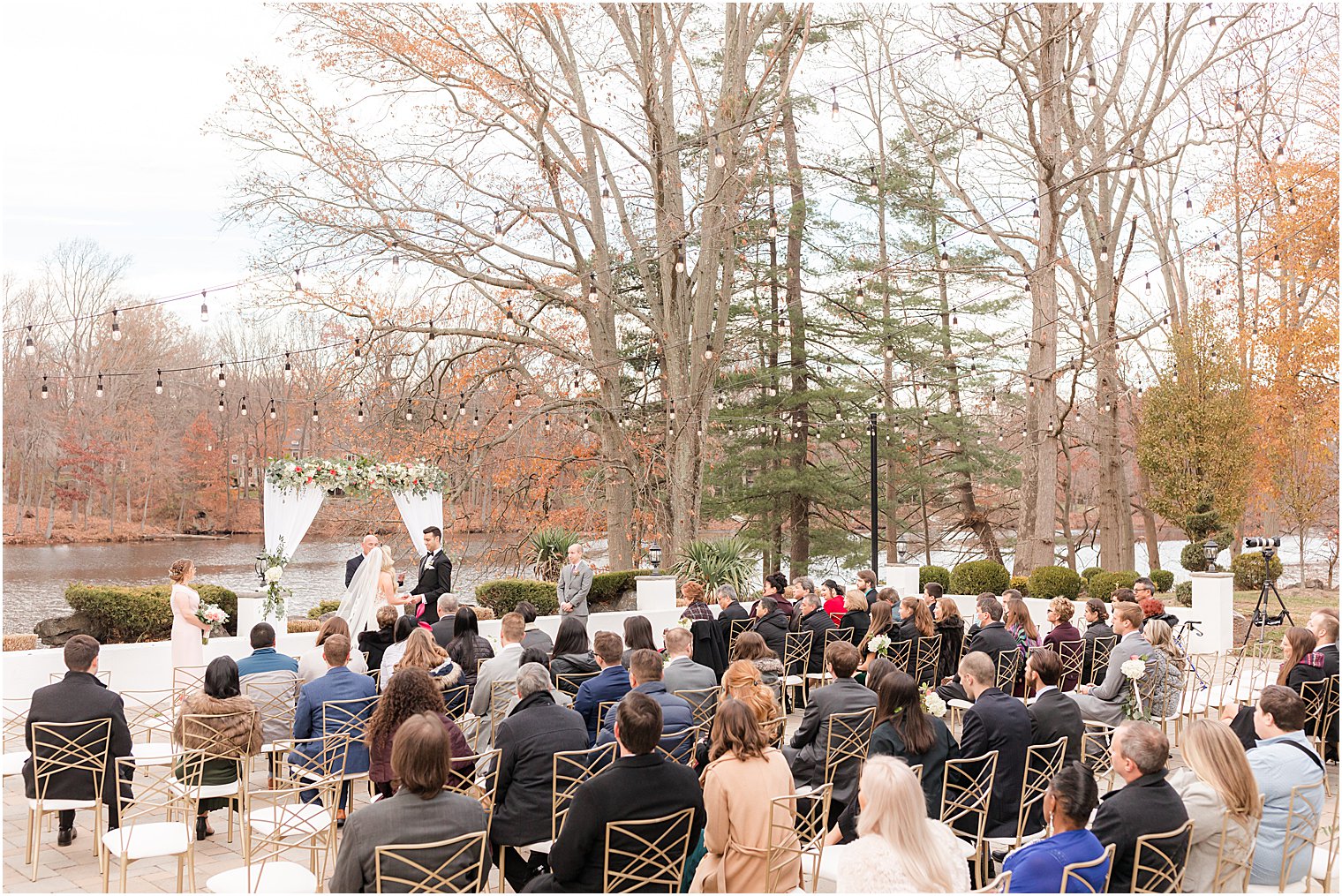 outdoor wedding ceremony in East Brunswick NJ with bistro lights and floral arbor 