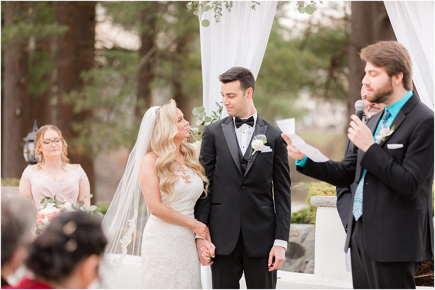 newlyweds hold hands looking at each other during outdoor wedding ceremony in East Brunswick NJ