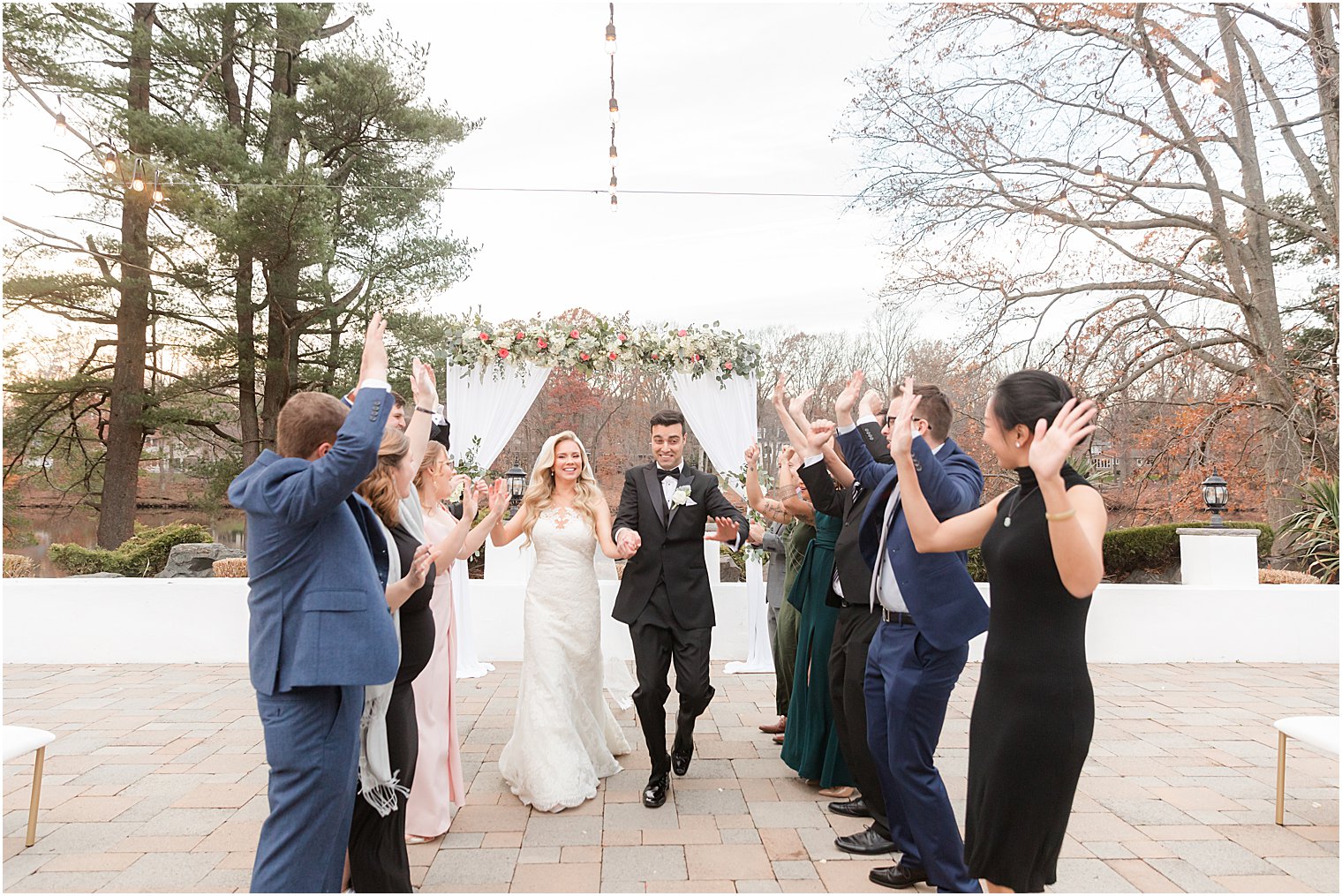 bride and groom hold hands walking through family