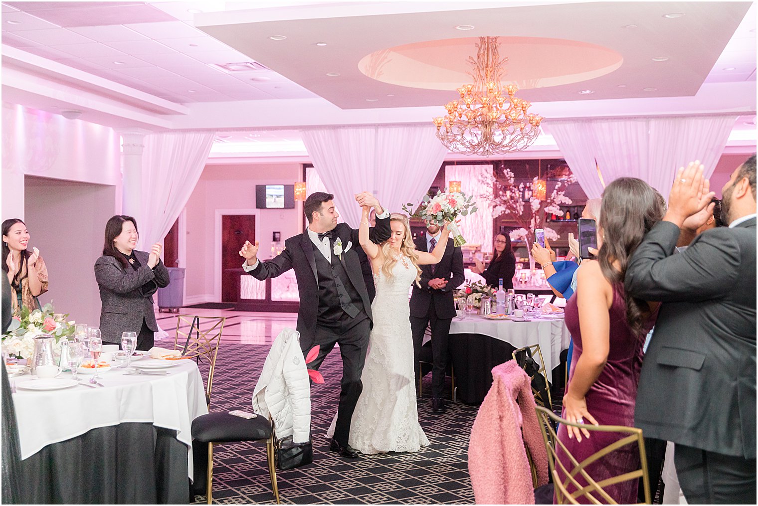 couple bumps hips entering wedding reception in New Jersey 