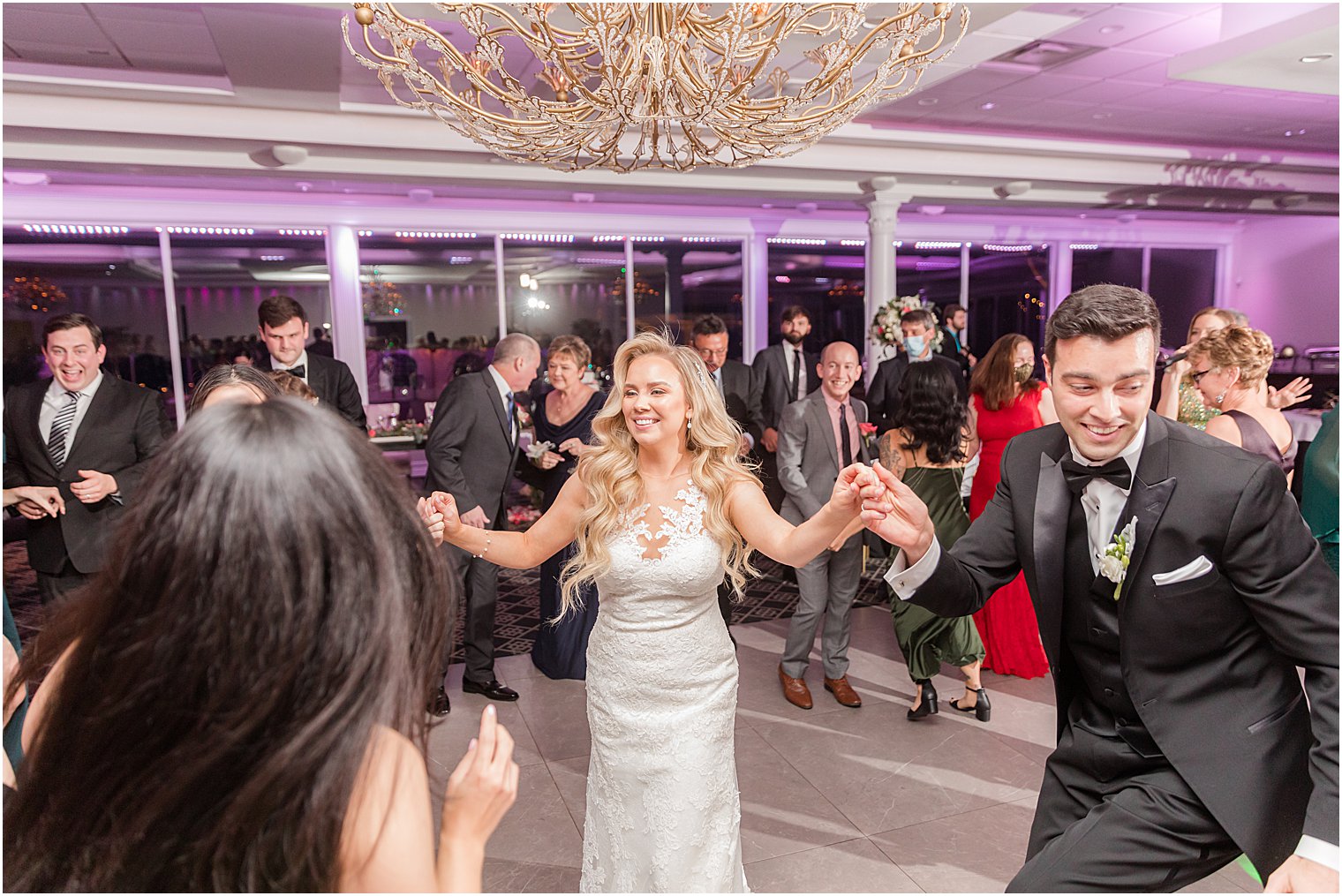 bride and groom hold hands dancing with wedding guests