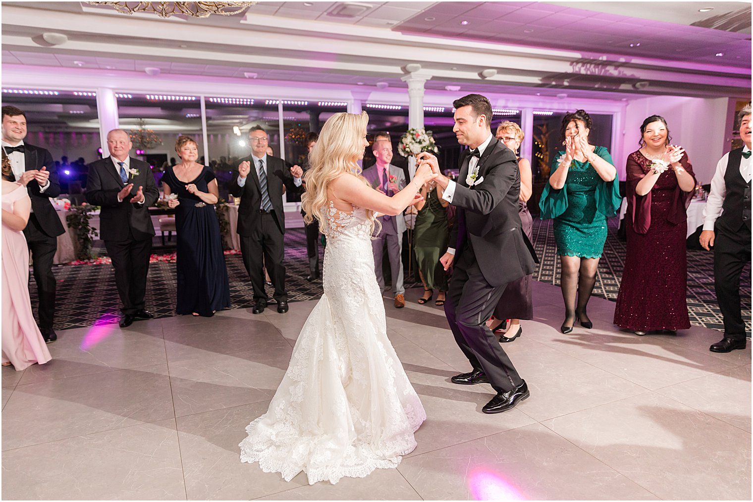 bride and groom hold hands dancing with guests around them in a circle