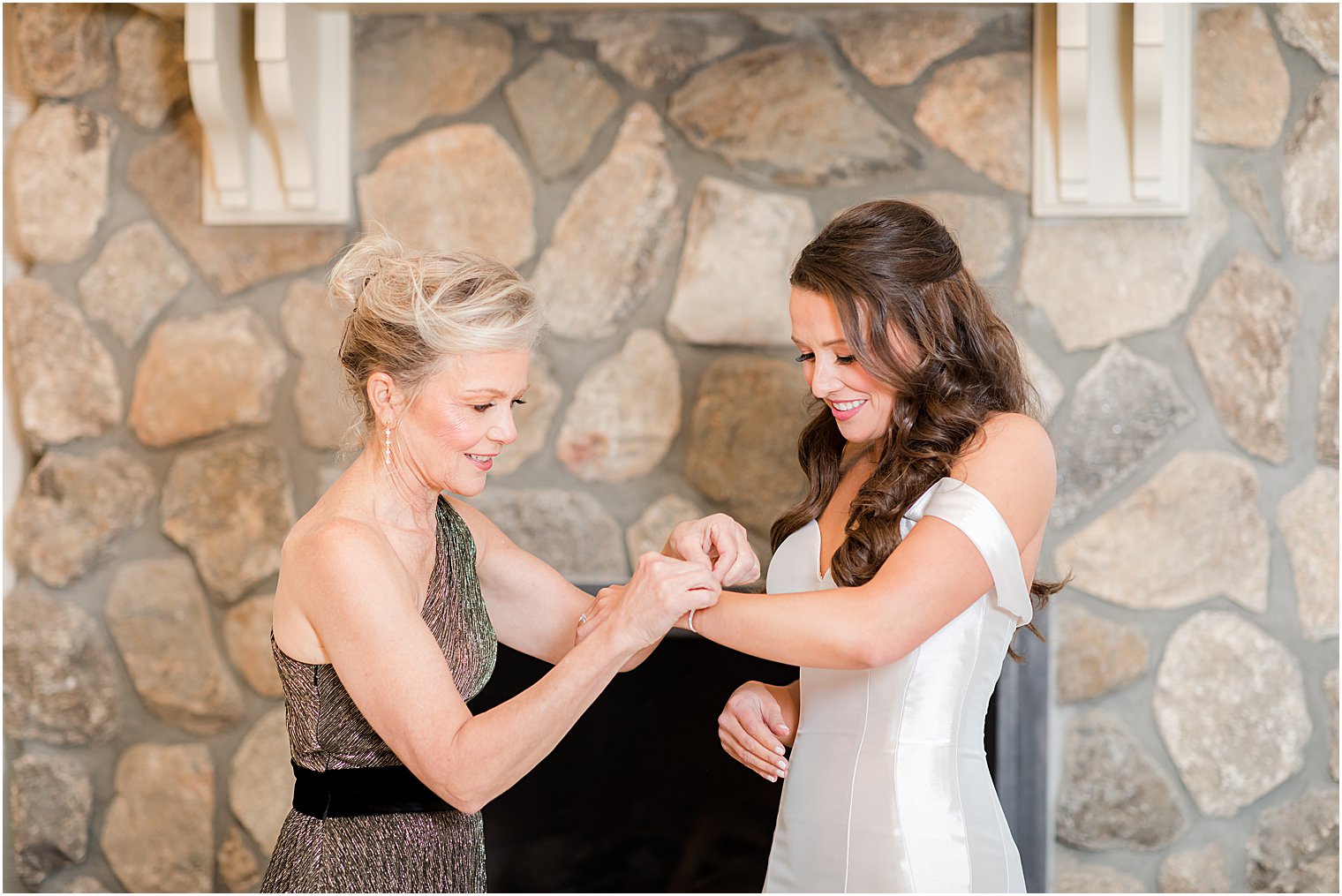 mother helps bride with jewelry on wedding morning 
