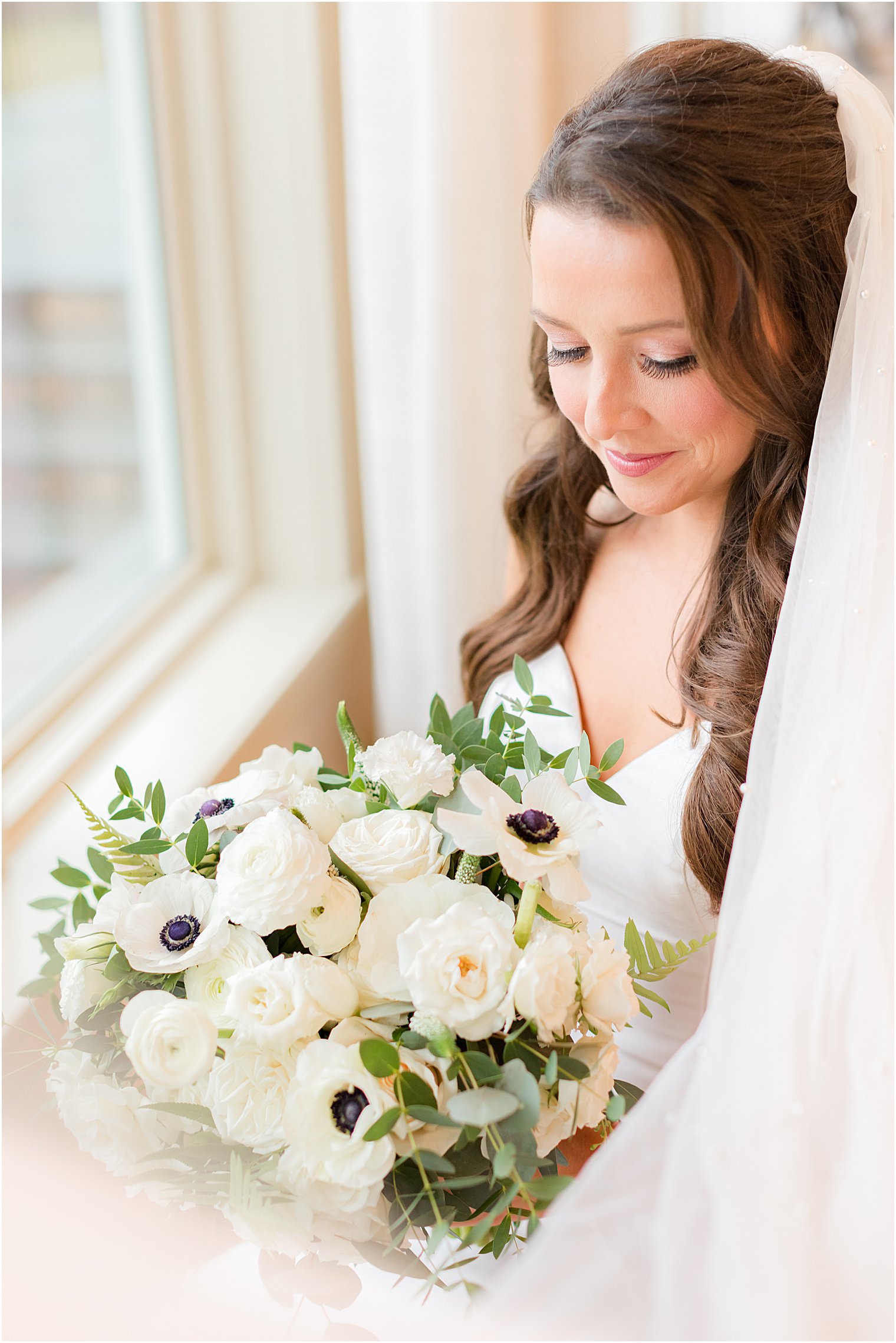 bride looks down at bouquet of flowers before winter wedding at Indian Trail Club