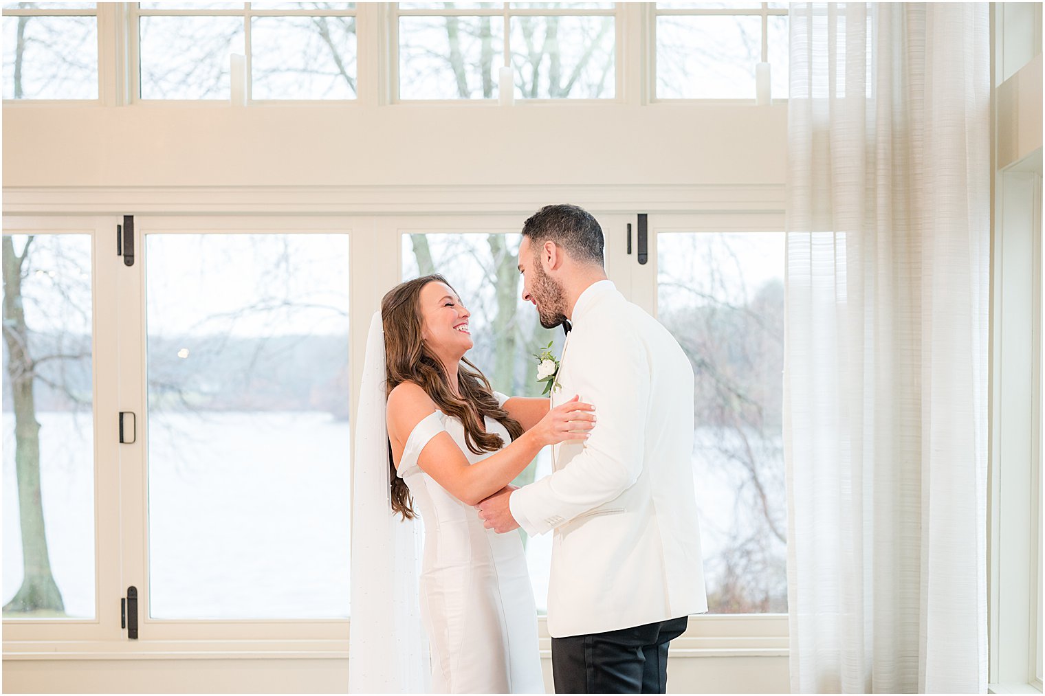 couple smiles together during first look before winter wedding