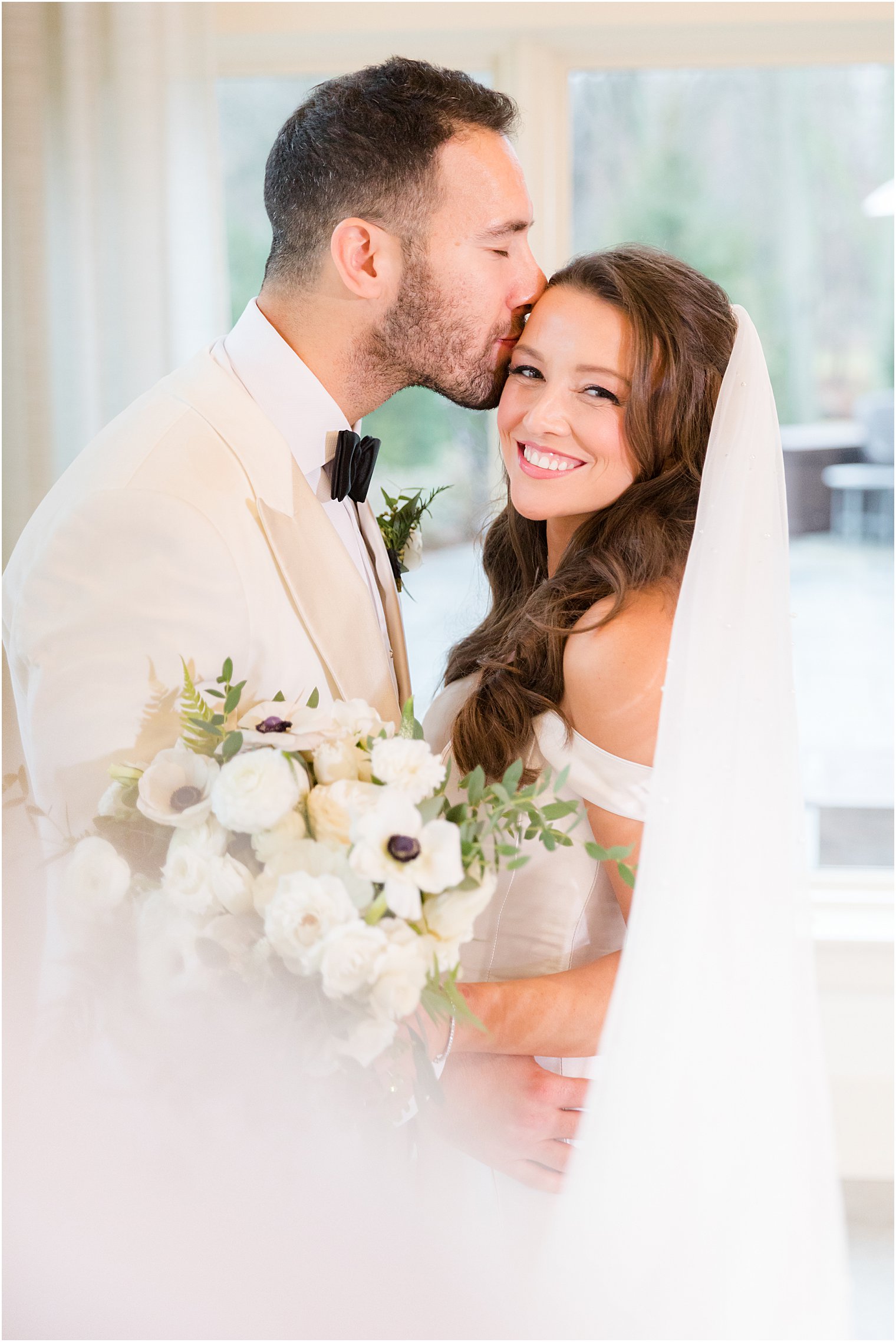 groom kisses bride's forehead during NJ wedding portraits 