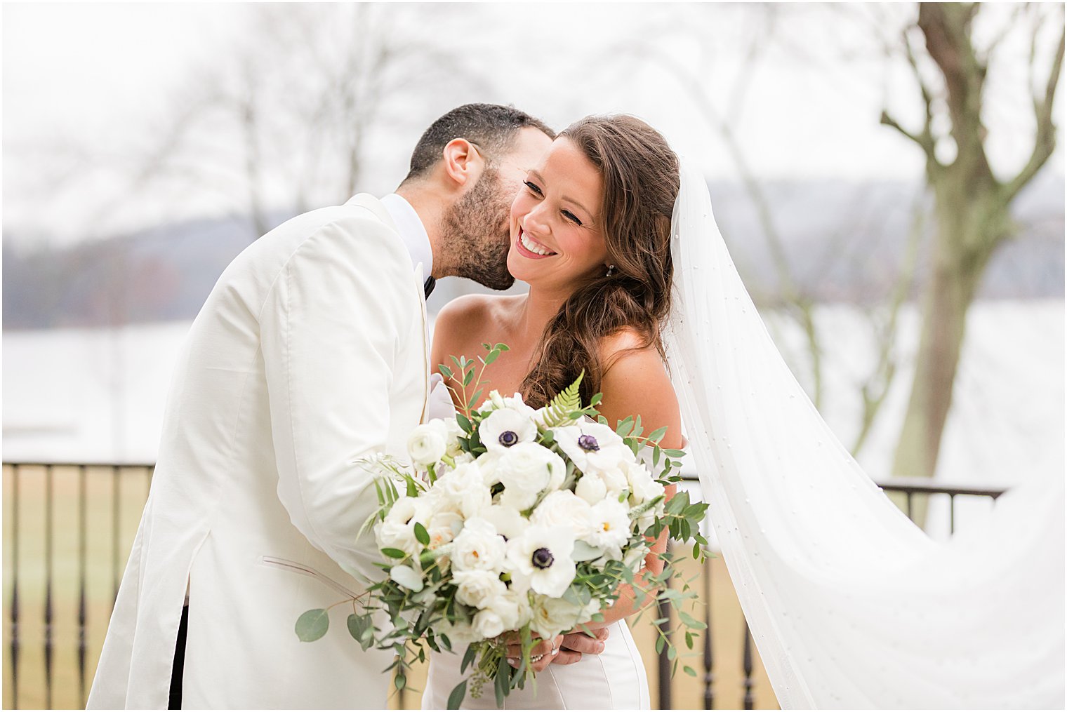 groom kisses bride's cheek making her laugh