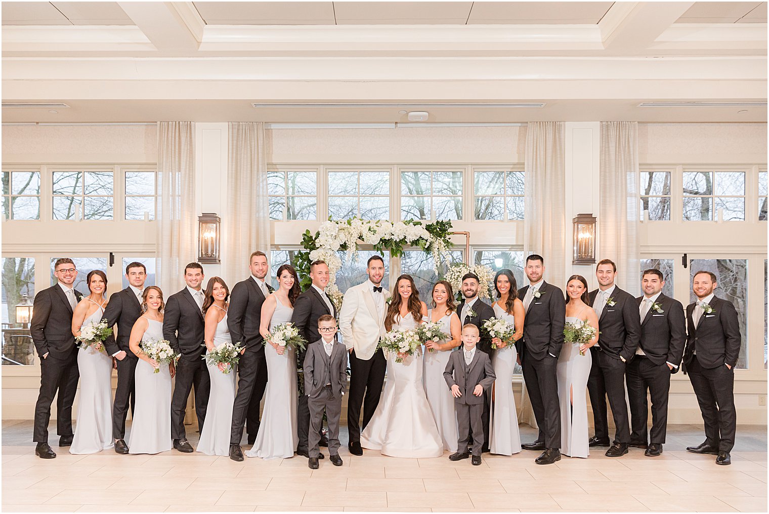 newlyweds pose with wedding party in grey and light blue gowns