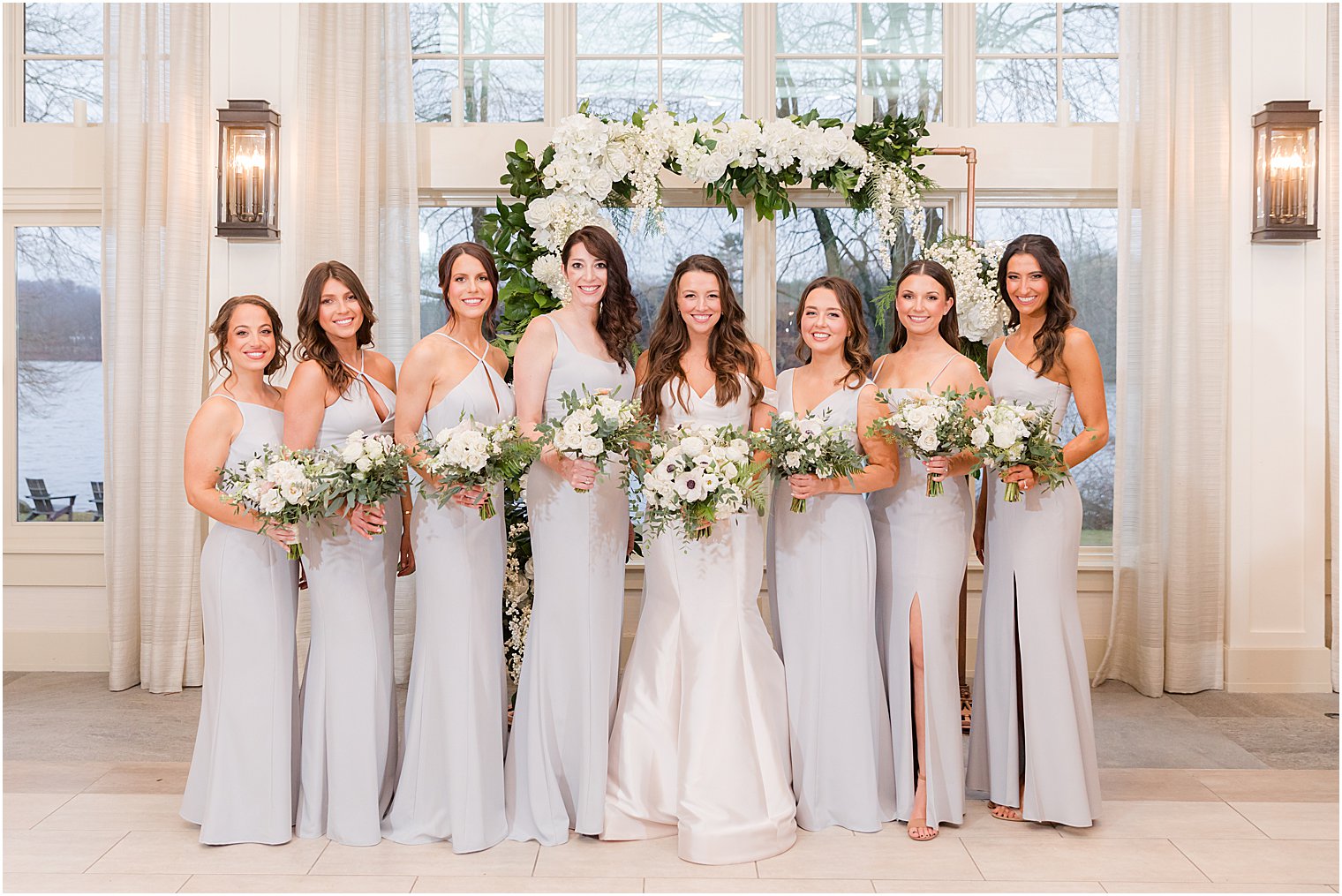 bride poses with bridesmaids in light blue gowns