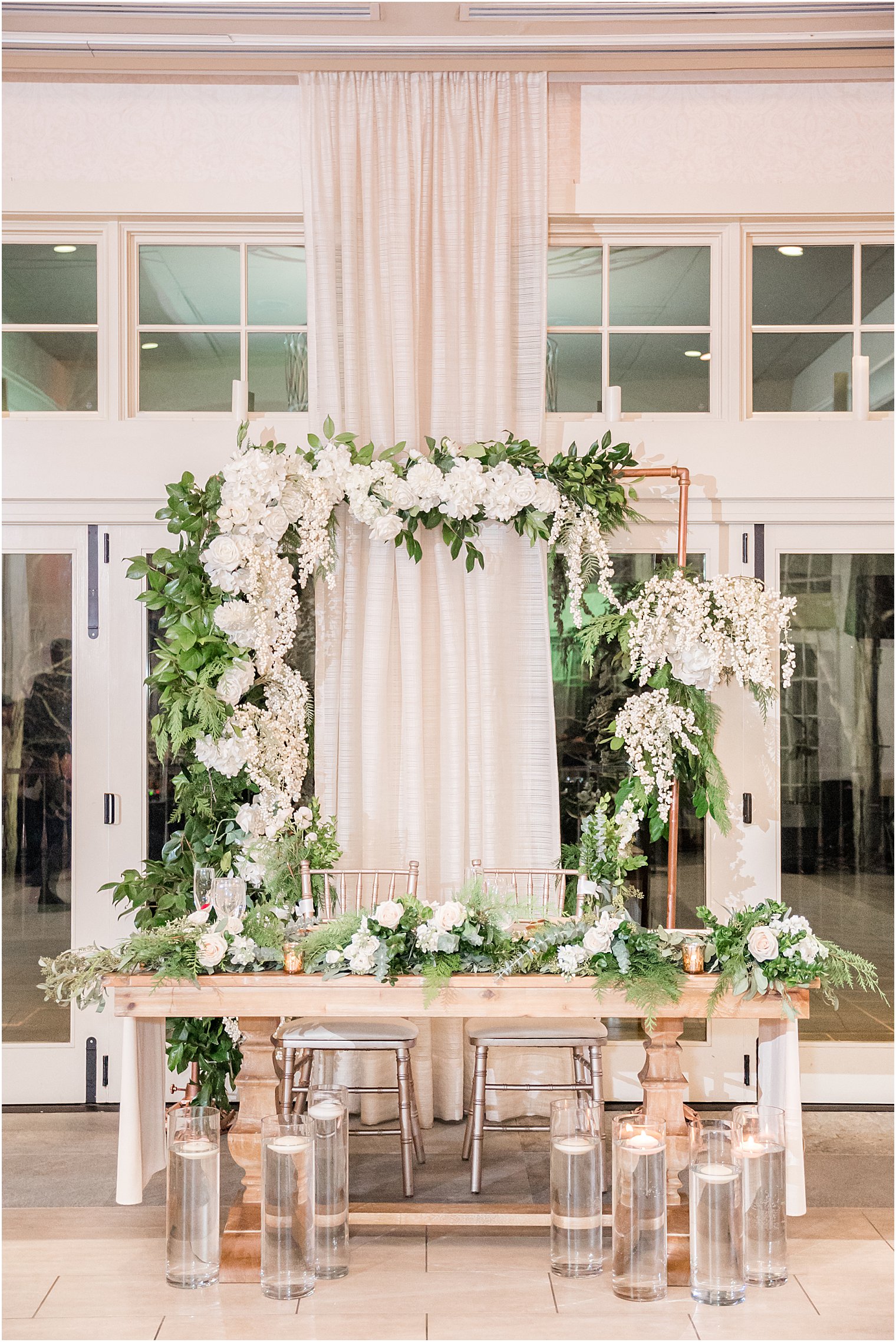 sweetheart table with white floral arbor
