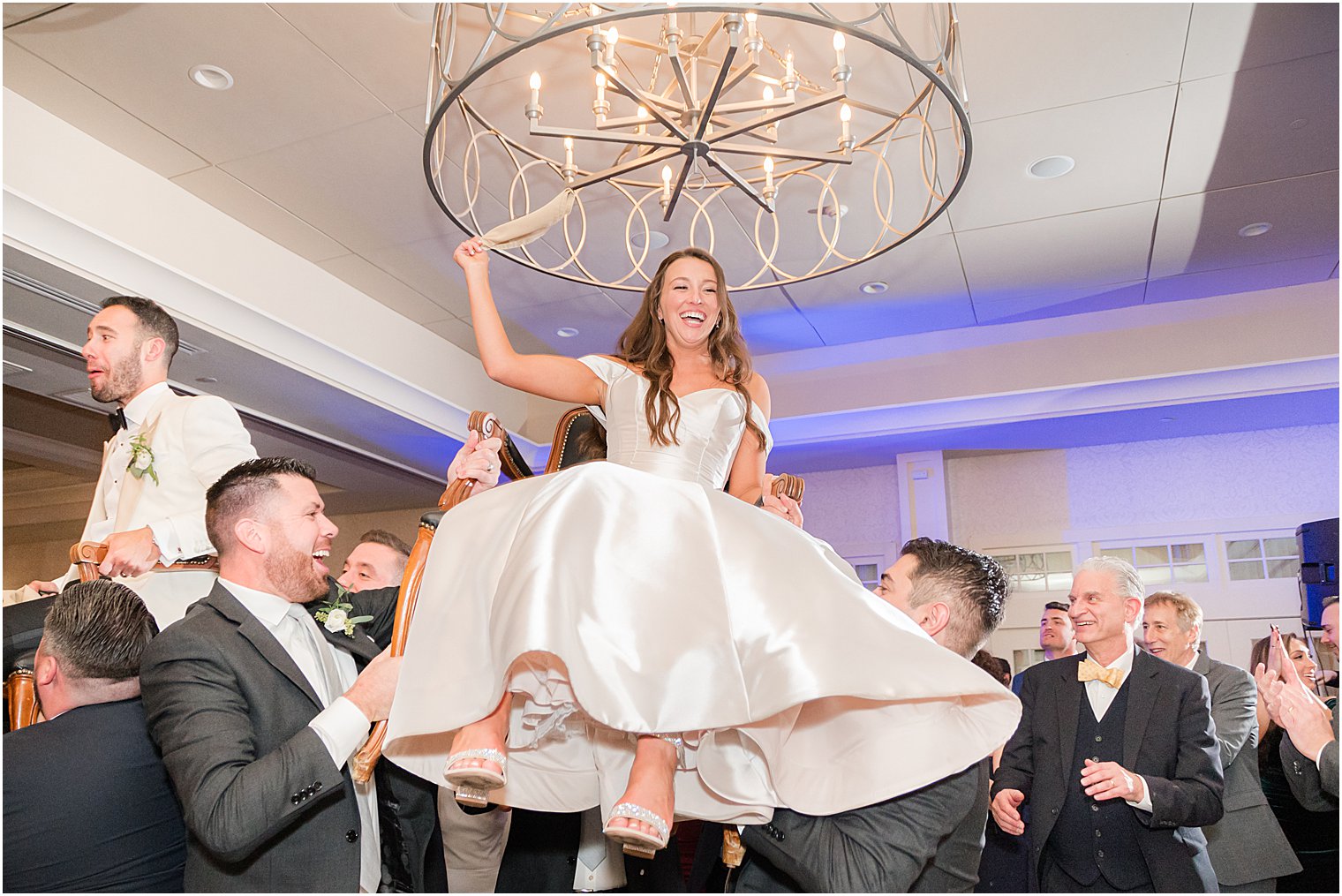 bride is lifted in chair during winter wedding reception