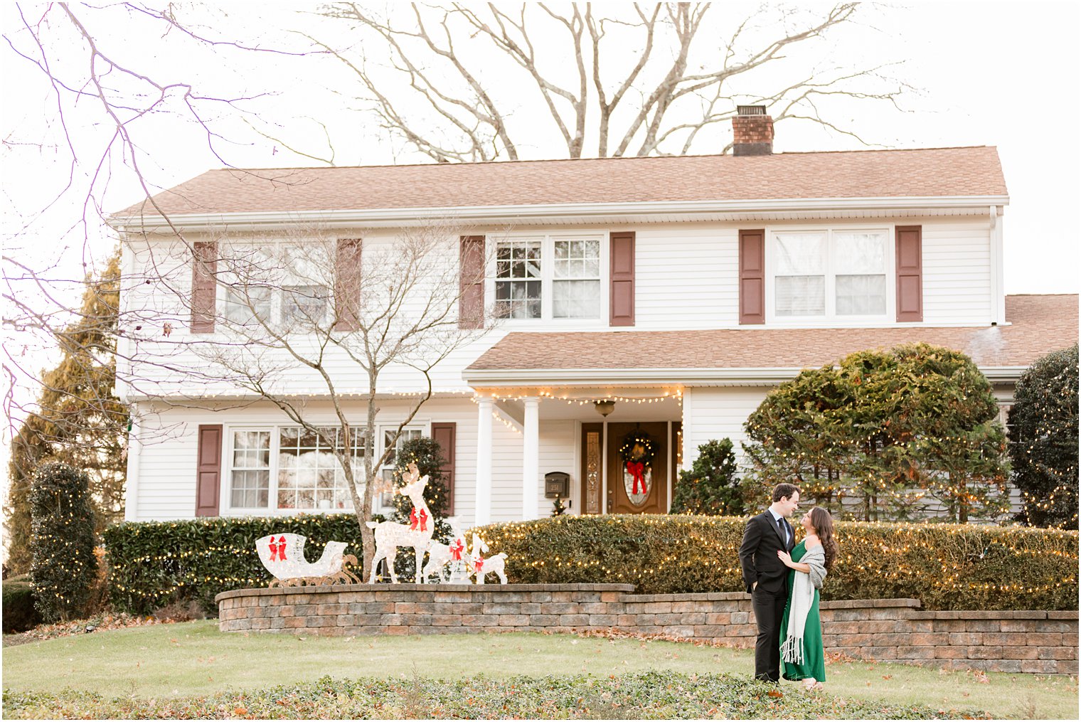bride and groom hug on lawn during holiday engagement session at home 