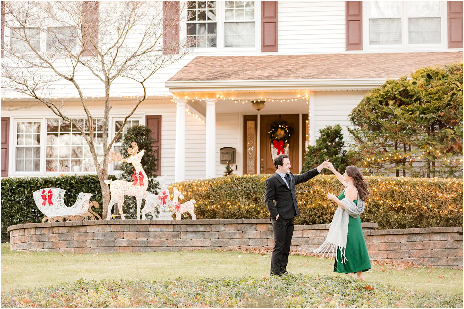 man twirls fiancee on lawn of their home during holiday engagement photos