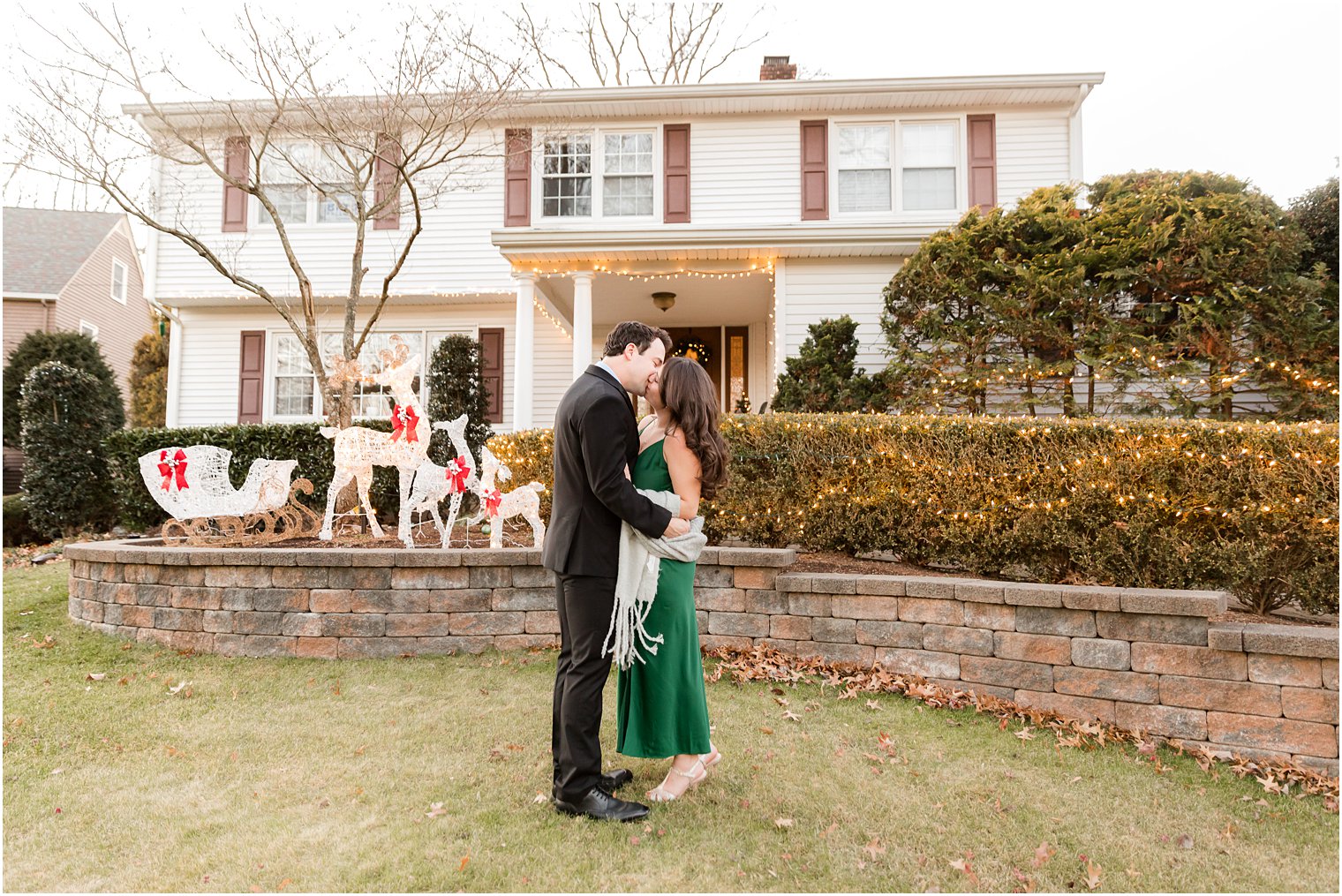 bride and groom kiss outside New Jersey home during holiday engagement session 