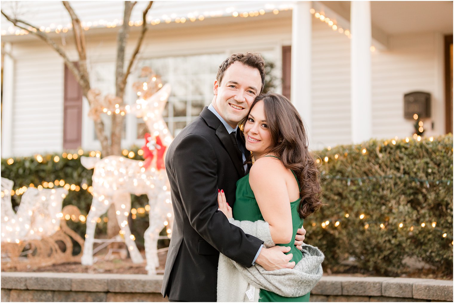 engaged couple hugs on front lawn during holiday engagement photos